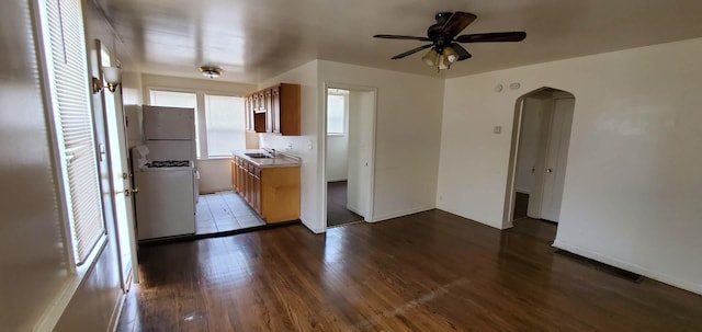 kitchen featuring a ceiling fan, a sink, wood finished floors, freestanding refrigerator, and arched walkways