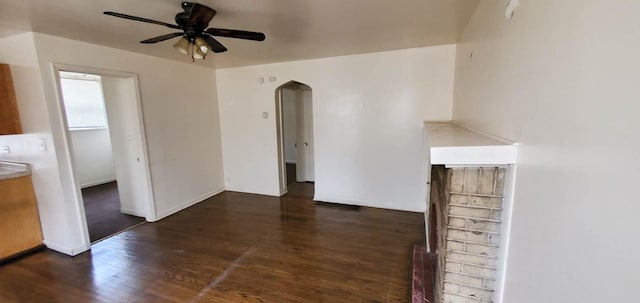 interior space with baseboards, arched walkways, wood finished floors, and a ceiling fan