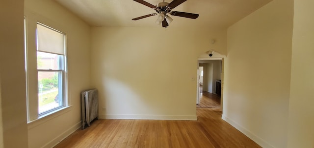 unfurnished room featuring radiator, baseboards, light wood-style floors, and a ceiling fan