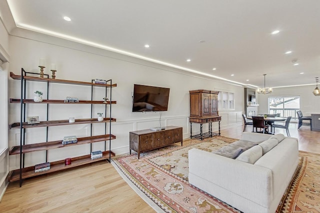 living area featuring an inviting chandelier, recessed lighting, wood finished floors, and ornamental molding