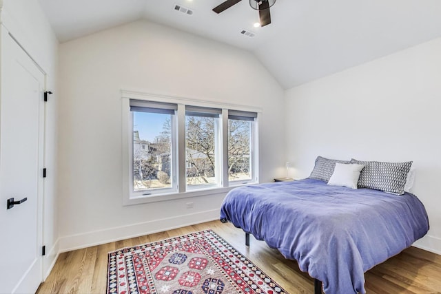 bedroom featuring visible vents, lofted ceiling, baseboards, and wood finished floors