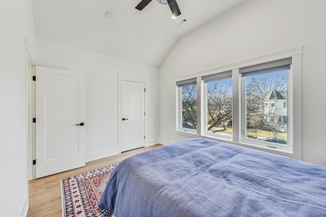 bedroom featuring visible vents, baseboards, ceiling fan, vaulted ceiling, and wood finished floors