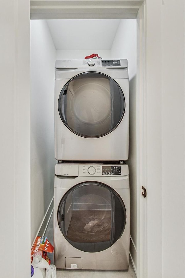 clothes washing area featuring baseboards, stacked washer and clothes dryer, and laundry area