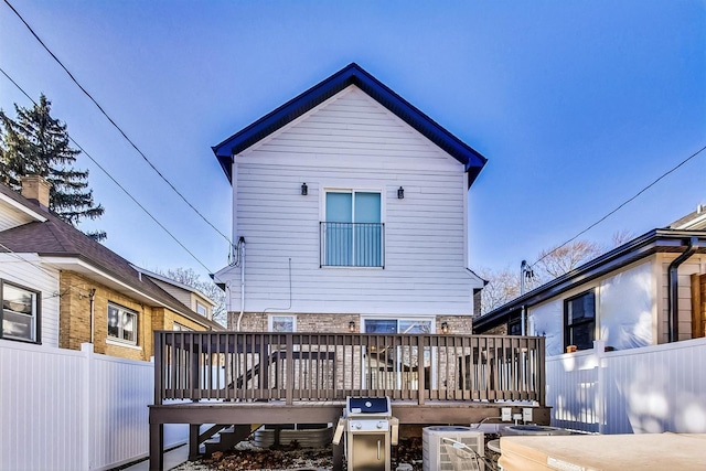 rear view of property with central AC unit, a deck, and fence