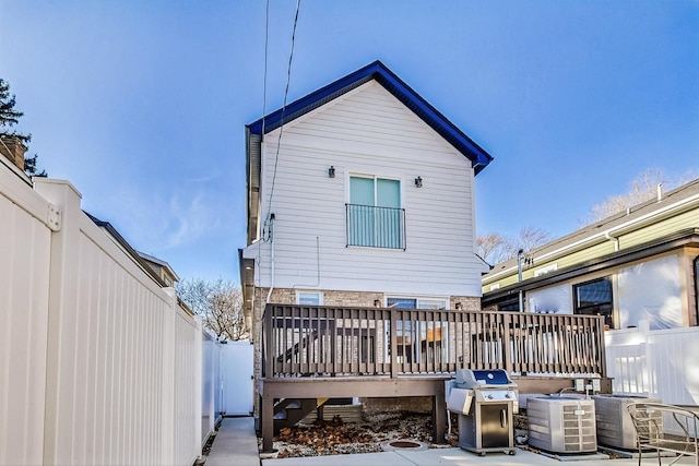 rear view of house with brick siding, central air condition unit, a deck, and fence