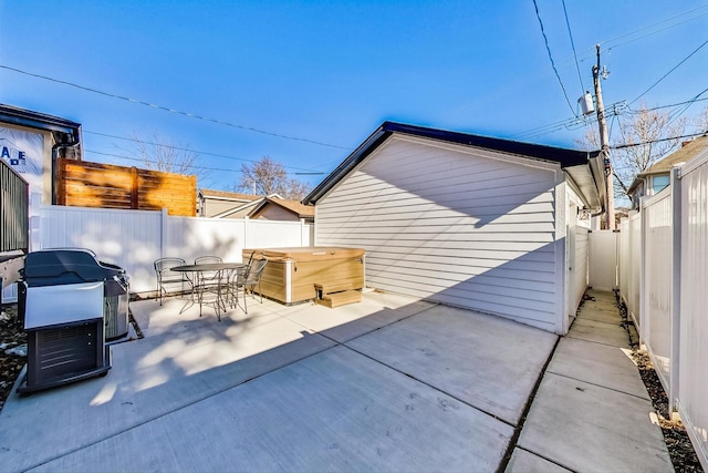 view of patio with outdoor dining space, a hot tub, and a fenced backyard