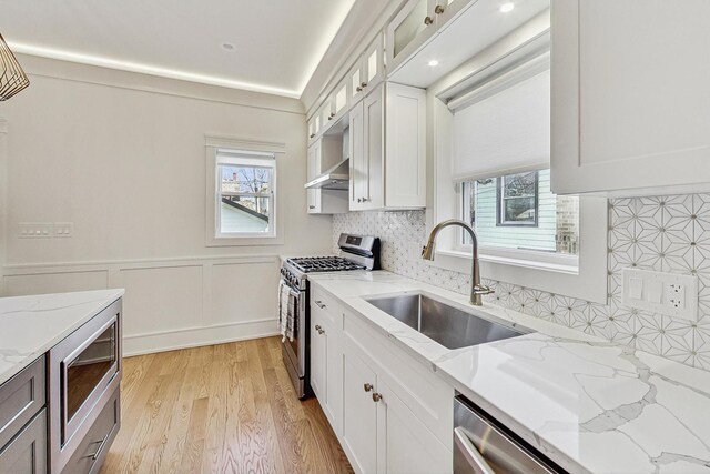 kitchen with a healthy amount of sunlight, appliances with stainless steel finishes, light wood-type flooring, and a sink