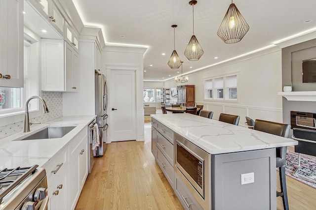 kitchen with a breakfast bar area, a kitchen island, a sink, appliances with stainless steel finishes, and open floor plan