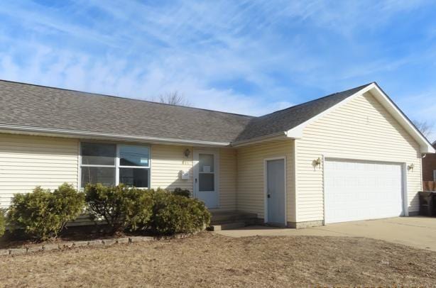 ranch-style house with a garage, driveway, and roof with shingles