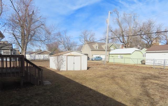 view of yard featuring an outbuilding, a residential view, a storage shed, and fence