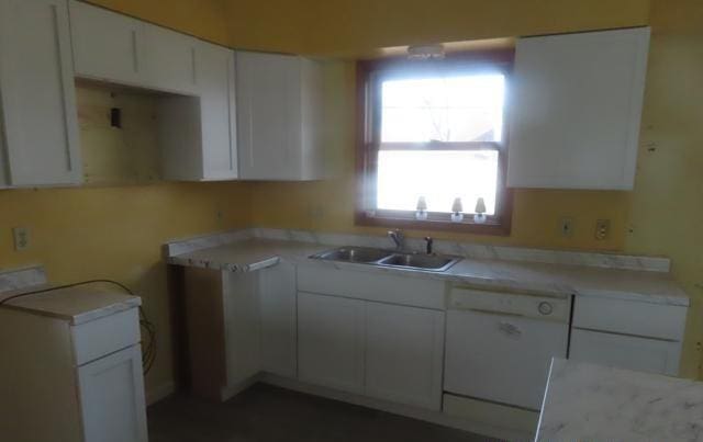 kitchen with a sink, white cabinets, white dishwasher, and light countertops