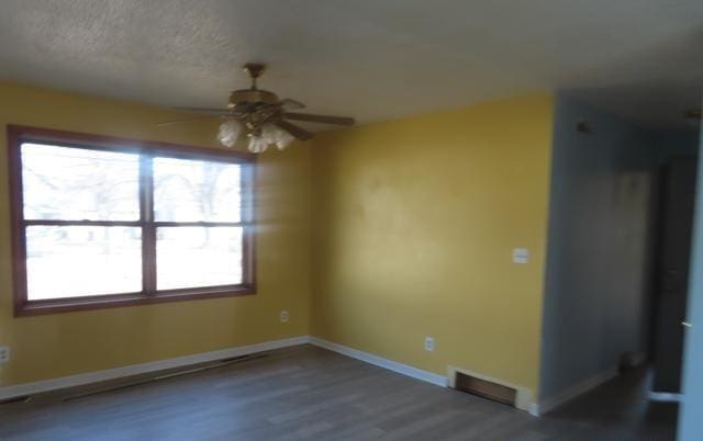 spare room with visible vents, baseboards, wood finished floors, a textured ceiling, and a ceiling fan