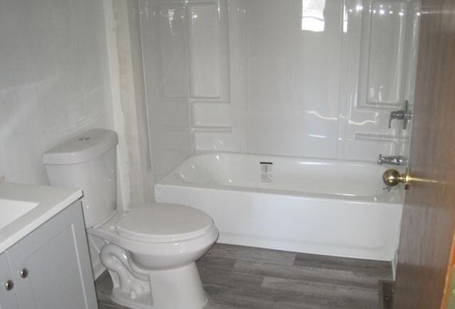 full bath featuring vanity, washtub / shower combination, toilet, and wood finished floors