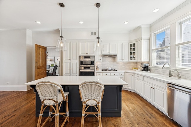 kitchen featuring visible vents, a sink, stainless steel appliances, under cabinet range hood, and tasteful backsplash