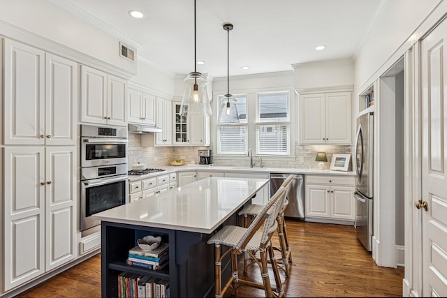 kitchen featuring visible vents, a sink, under cabinet range hood, white cabinetry, and stainless steel appliances