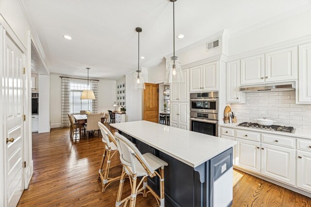 kitchen with white cabinets, double oven, gas stovetop, and ornamental molding