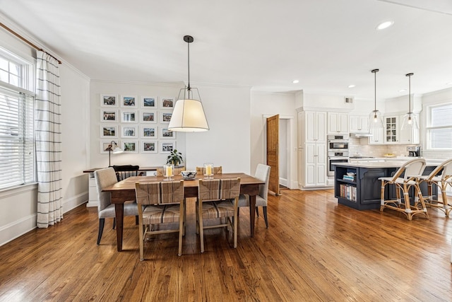 dining room with crown molding, wood finished floors, and baseboards