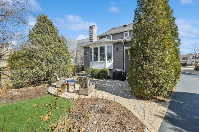 back of property with a patio, fence, and a chimney