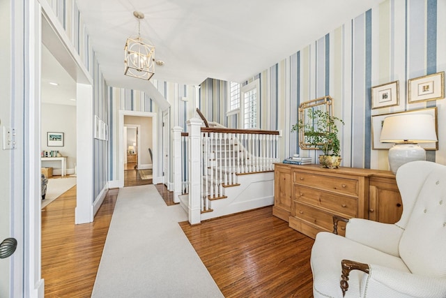 interior space featuring wallpapered walls, wood finished floors, and a chandelier