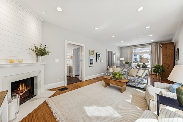 living area featuring visible vents, wood finished floors, recessed lighting, a premium fireplace, and baseboards