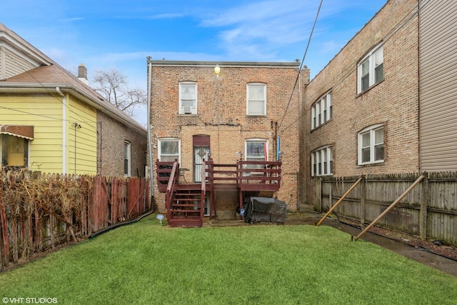 rear view of property with brick siding, a fenced backyard, a lawn, and a deck