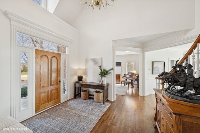 entrance foyer with plenty of natural light, high vaulted ceiling, an inviting chandelier, and wood finished floors