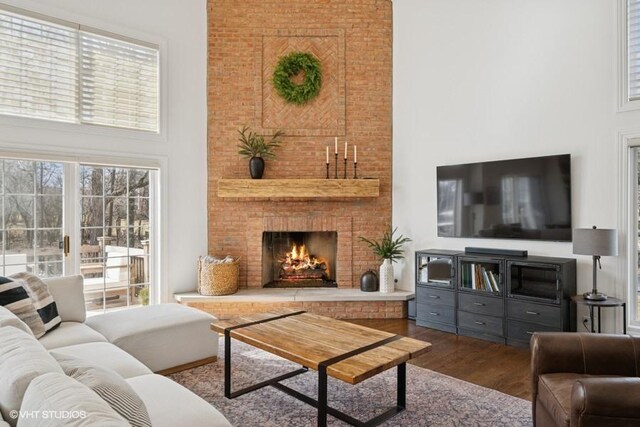 living area featuring a fireplace, wood finished floors, and a towering ceiling