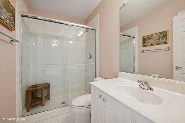 full bath with vanity, toilet, a stall shower, and tile patterned flooring