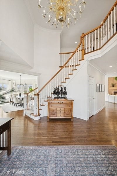 stairway with wood finished floors, baseboards, a towering ceiling, and ornamental molding