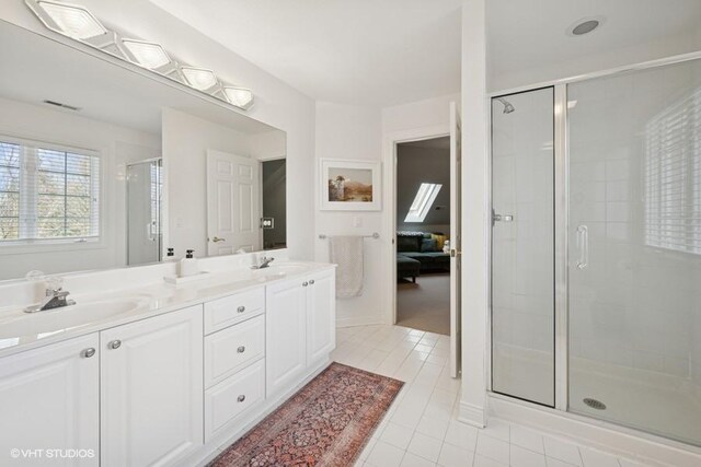 ensuite bathroom featuring visible vents, a sink, a shower stall, tile patterned flooring, and double vanity