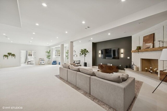 living area featuring carpet flooring, recessed lighting, visible vents, and a fireplace with raised hearth