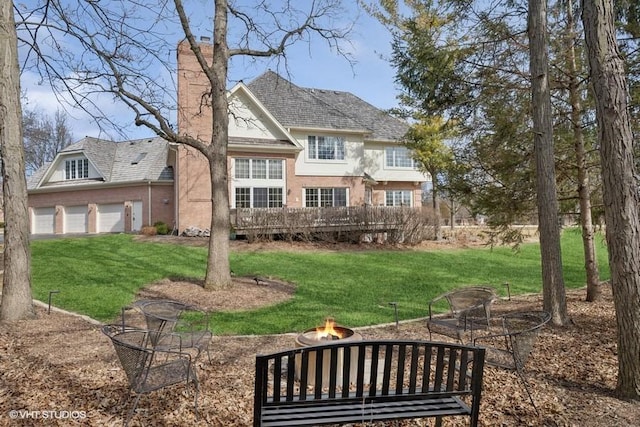 back of house with brick siding, a yard, a fire pit, and a garage