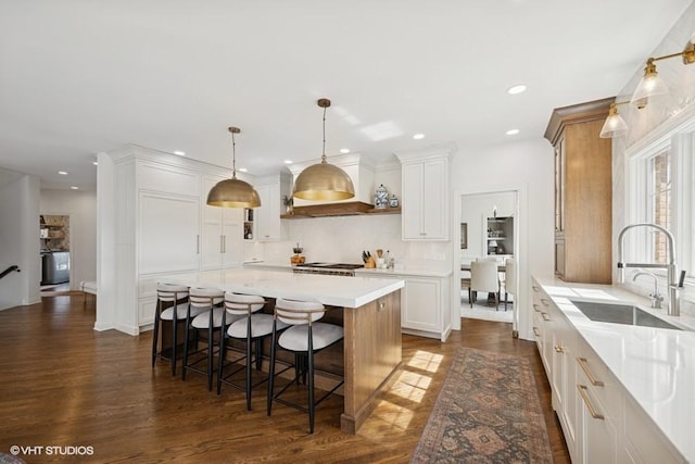 kitchen with tasteful backsplash, a center island, a breakfast bar, white cabinets, and a sink