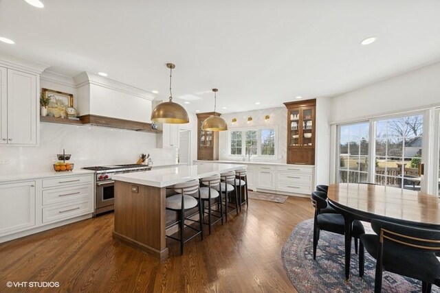 kitchen featuring a breakfast bar, stainless steel stove, dark wood-type flooring, and a center island