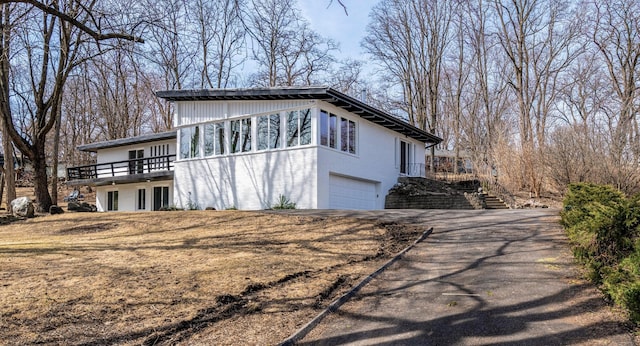 exterior space featuring stairway, an attached garage, and driveway