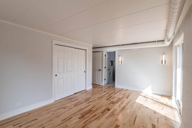 unfurnished bedroom featuring crown molding, light wood-style flooring, and baseboards