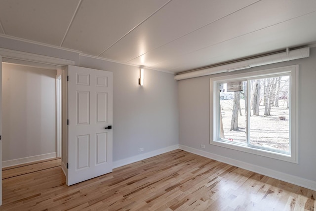 spare room with light wood-style flooring, baseboards, and ornamental molding