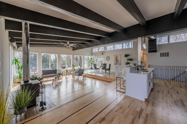 living area with visible vents, beamed ceiling, a healthy amount of sunlight, and light wood-style flooring