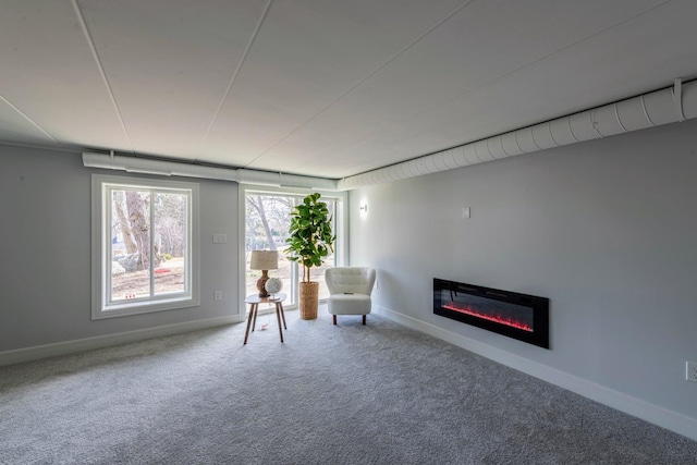 unfurnished room featuring a glass covered fireplace, baseboards, and carpet