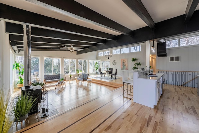 living room with beamed ceiling, visible vents, a healthy amount of sunlight, and light wood-style floors