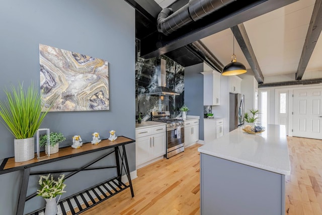 kitchen with appliances with stainless steel finishes, wall chimney exhaust hood, white cabinets, and light countertops