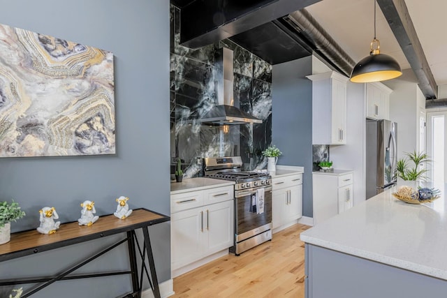 kitchen featuring appliances with stainless steel finishes, wall chimney exhaust hood, white cabinets, and light countertops