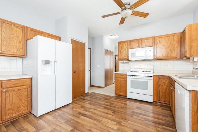 kitchen with white appliances, light wood-style flooring, a sink, light countertops, and tasteful backsplash