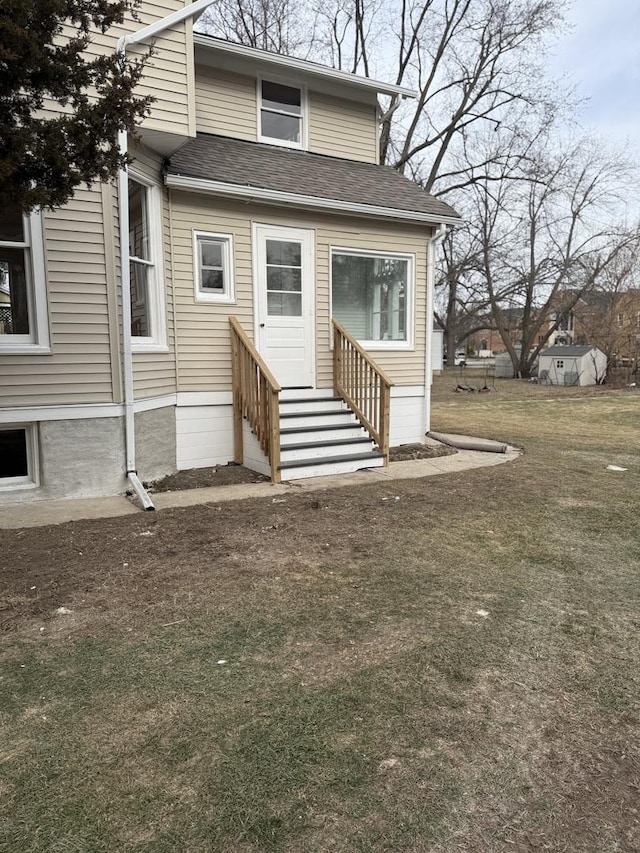 view of front of house with a shingled roof, a front yard, and entry steps