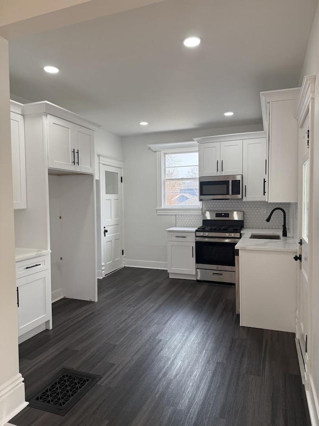 kitchen featuring visible vents, dark wood-type flooring, white cabinetry, appliances with stainless steel finishes, and light countertops