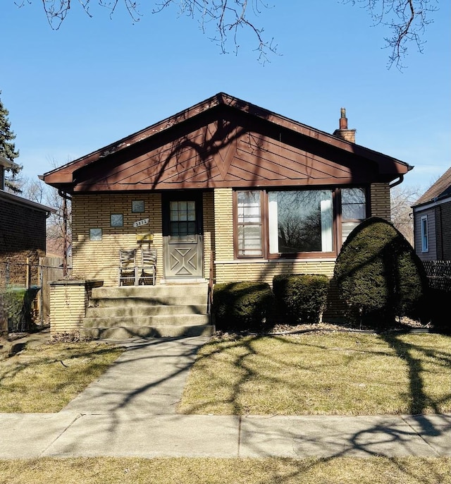 bungalow-style home featuring a chimney, a front lawn, and fence