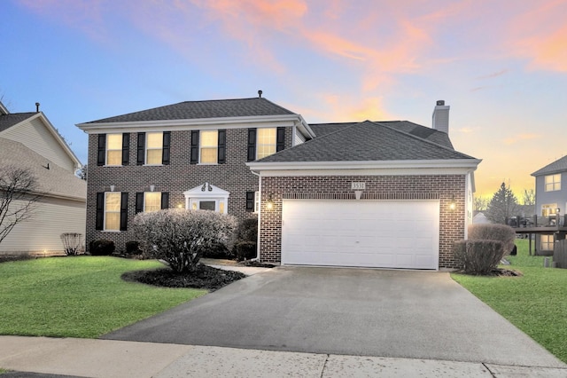 colonial-style house featuring a yard, brick siding, concrete driveway, and an attached garage