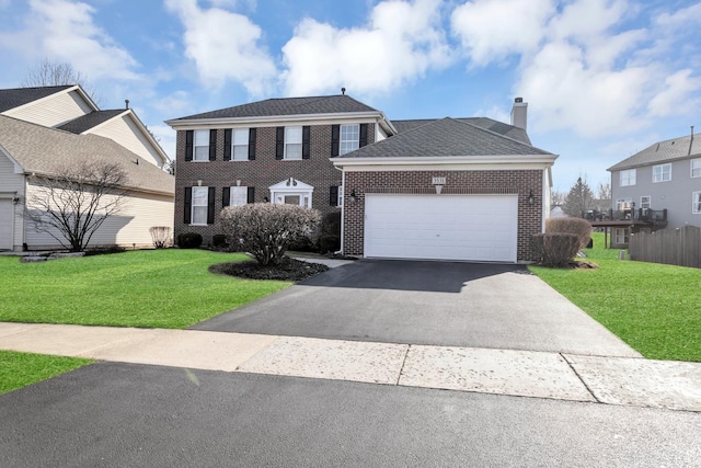 colonial house with driveway, brick siding, an attached garage, and a front lawn