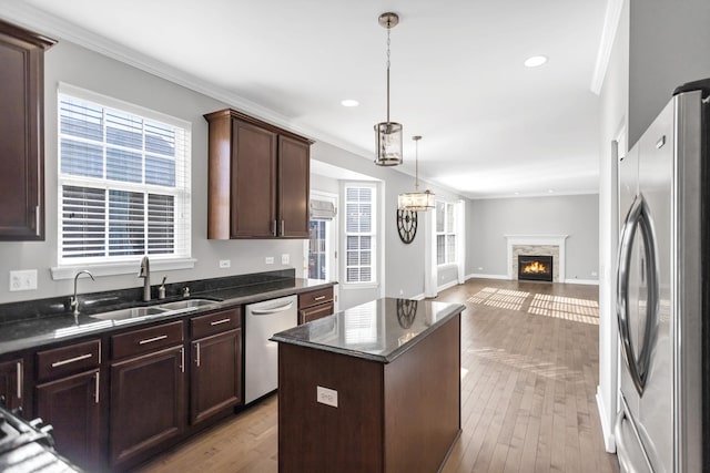 kitchen with a center island, open floor plan, ornamental molding, appliances with stainless steel finishes, and a sink