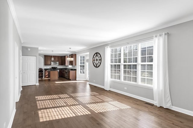 unfurnished living room featuring crown molding, baseboards, dark wood-style flooring, and a chandelier